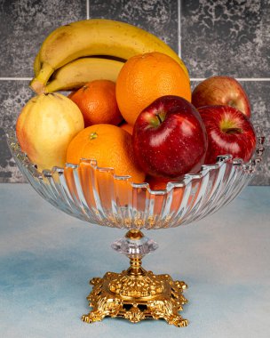 Ahşap bir masada, cam bir kasedeki olgun meyvelerin çeşitliliği, ev dekorasyonları.