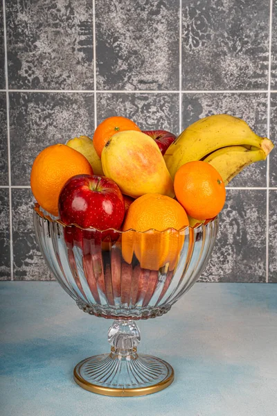 stock image Variety of ripe fruits in a stylish glass bowl on a wooden table,home decorations