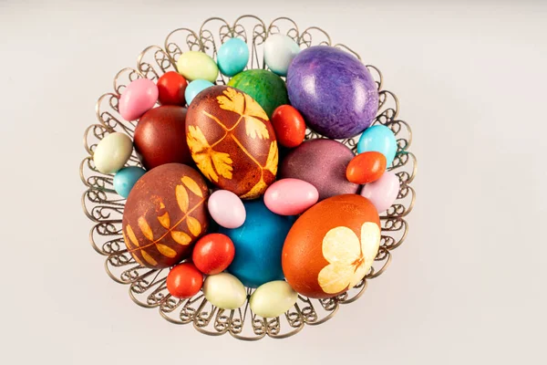 stock image Multicolored Easter eggs and sweeties in a metal bowl together at white background. Pastel colored Easter eggs and sweeties