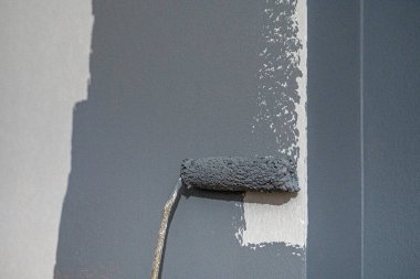 Boya silindirli erkek el boyası duvar. Daire boyama, beyaz boyayla yenileme.