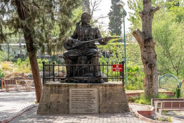 Tarsus,Mersin Turkey , April 19 2024: Statue of the famous folk poet Karacaoglan in the garden of the alayan Waterfalls. clipart