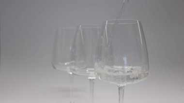Beyaz şarap. Şarap beyaz arka planda bir bardağa dökülüyor. Yakın plan çekim. Bardakta buz. Yüksek kalite 4k görüntü