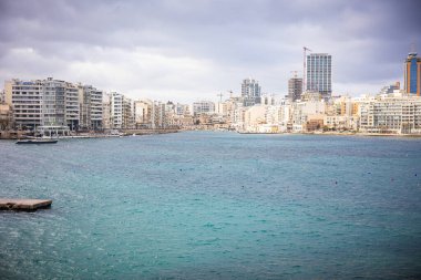 General view of the city under construction through the water barrier. Sea, coastal city. Malta. High quality photo