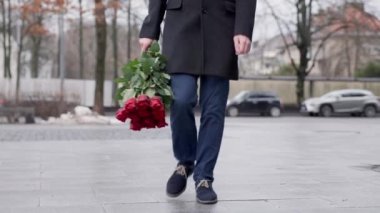 A man with a bouquet of roses on the street walks forward in a hurry to meet. Valentines Day. High quality 4k footage