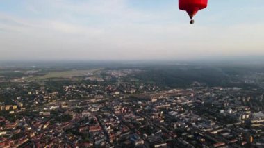 Sıcak hava balonunun yazın, gün batımında, yaz akşamında şehrin üzerinde yükselmesi. Litvanya, Vilnius, Haziran 2022. Yüksek kaliteli FullHD görüntüler