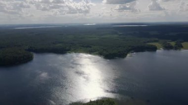 Güneş ışınları nehrin suyuna yansıyor. Suyun üzerindeki güneş yolu. Orman ve nehir. Hava görüntüsü. Bir İHA 'dan ateş etmek. Yüksek kaliteli FullHD görüntüler