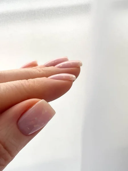 Womans hand with fresh manicure and delicate pink polish shape nail soft square. High quality photo