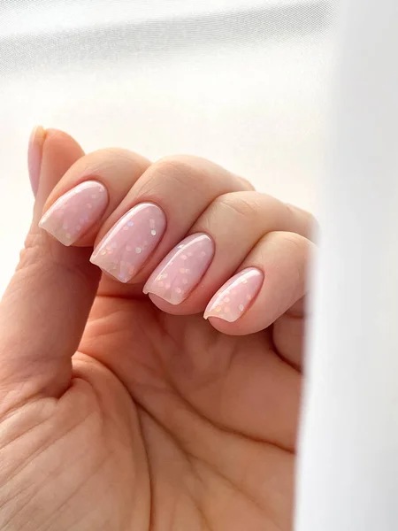 Womans hand with fresh manicure and delicate pink polish shape nail soft square. High quality photo
