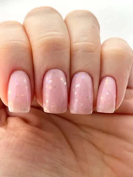 Womans hand with fresh manicure and delicate pink polish shape nail soft square. High quality photo