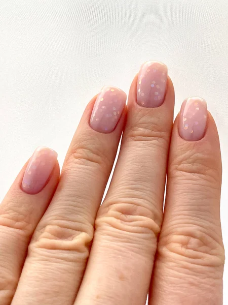 New manicure. Womans hand with fresh manicure and delicate pink polish. The shape of the nail is a soft square.Edged manicure. High quality photo