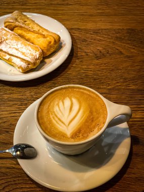 Bir fincan kahveli latte ve ahşap bir masada pasta. Lezzetli kahvaltı. Yüksek kalite fotoğraf
