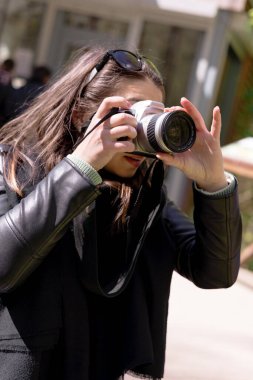 Genç bir kız elinde bir kamera tutuyor. Koyu renk saçlı, sonbahar manzaralı. Kadın fotoğrafçı kavramı, kadın sanatı. Yüksek kalite fotoğraf