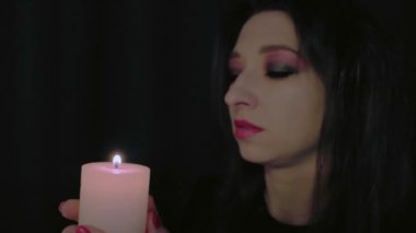 Genç vampir kız yanan mum üflüyor Cadılar Bayramı kutlaması konsepti mum alevi üzerine odaklan yüksek kaliteli 4K görüntü