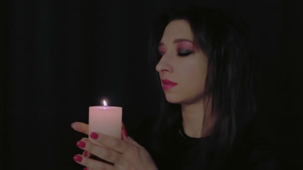 一个女孩在黑暗中吹灭了一支蜡烛 一个女人的脸的特写神奇的光晕之间的概念 高质量的4K镜头 — 图库视频影像