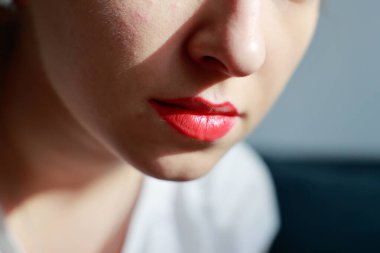 Kız dudaklarını fırçayla kırmızı rujla boyuyor. Yakın çekim, güneş ışınları, ev makyajı konsepti. Yüksek kalite fotoğraf