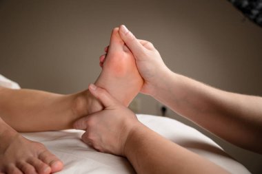 Bir terapistin ellerine, bir müşterinin ayağına masaj yaparken yaklaş. Ayak refleksolojisi ve rahatlama konsepti. Yüksek kalite fotoğraf
