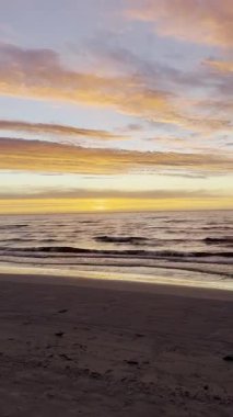 Sakin denizlerde gün batımı, hafif dalgalar ve parlayan turuncu bulutlar. Huzurlu deniz manzarası. Doğal ışık ve akşam gökyüzü. Poster, afiş, kart, davetiye, kopya alanı olan duvar kağıdı için tasarım. Yüksek kalite 4k görüntü