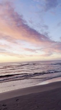 Sakin denizlerde gün batımı, hafif dalgalar ve parlayan turuncu bulutlar. Huzurlu deniz manzarası. Doğal ışık ve akşam gökyüzü. Poster, afiş, kart, davetiye, kopya alanı olan duvar kağıdı için tasarım. Yüksek kalite 4k görüntü