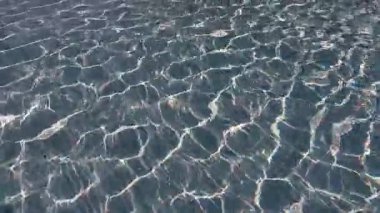 Güneş ışığı yüzme havuzunda su yüzeyine yansıyor. Kiremit desenli. Soyut arkaplan dokusu. Yaz tatili ve rahatlama konsepti. Duvar kağıdı için tasarlanmış Yüksek kalite 4k görüntü