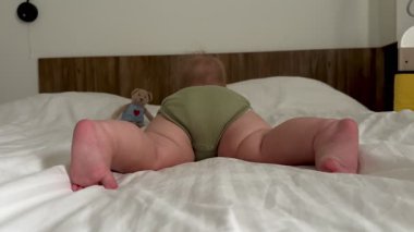 Yeşil bir kıyafetle beyaz bir arka planda sürünmeye çalışan küçük bir çocuğun ayakları. Yüksek kalite 4k görüntü