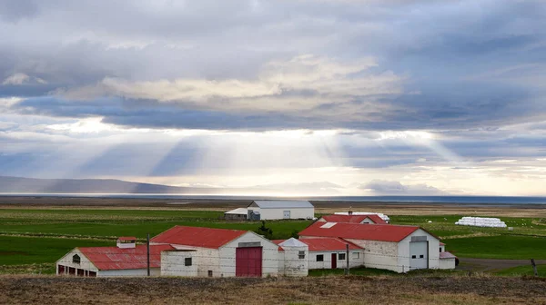 Bulutların arasından yükselen devasa güneş ışınları olan bir çiftlik, Altın Daire rotası, İzlanda Avrupa