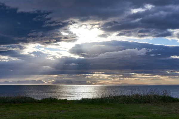 Bulutların arasından yükselen devasa güneş ışınları olan göl, Altın Daire rotası, İzlanda Avrupa
