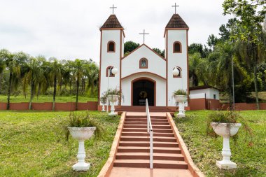 facade of a small white catholic chapel with brown stairs in Brazil