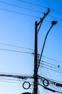 Elektrik direğine bağlı birçok kablo, elektrik direğindeki kablolar ve kablolar karmaşası, mavi gökyüzü arka planı, Brezilya 'daki teknolojik kombinasyon konsepti