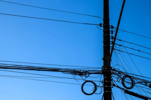 Many wires attached to the electric pole, the chaos of cables and wires on an electric pole, blue sky background, technological combination concept in Brazil