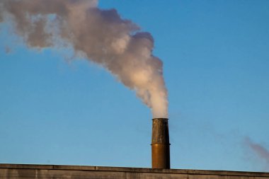 Brezilya 'da mavi gökyüzü arkaplanı olan bir fabrikanın bacaları tütüyor.