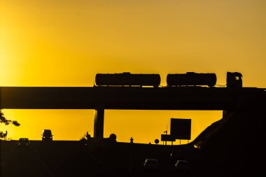 Muhteşem altın gün batımında otoyolların kesiştiği yerde seyahat eden araçların silueti.