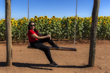 Brezilya 'da bir ayçiçeği tarlasının yanında siyah saçlı ve siyah gözlüklü orta yaşlı bir kadının portresi.