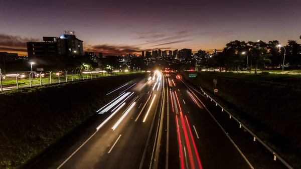 Trail of light caused by vehicular traffic in Highway with buildings from downtown in the background, in Marilia,