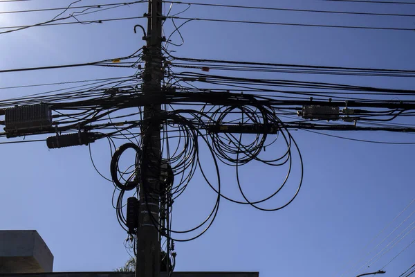 Many wires attached to the electric pole, the chaos of cables and wires on an electric pole, blue sky background, technological combination concept in Brazil