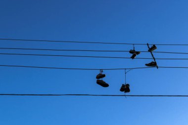 Brezilya 'da gökyüzüne karşı elektrik teli üzerinde asılı eski ayakkabılar. Ayakkabı fırlatma