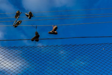 Brezilya 'da bir gökyüzüne karşı tel örgü örgüler ve eski ayakkabılar asılıydı. Ayakkabı fırlatma