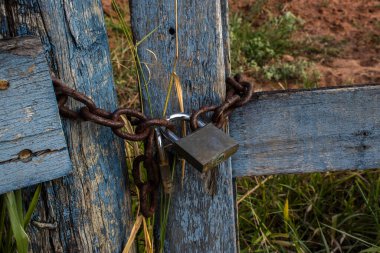 Asma kilit, Brezilya 'nın kırsal kesiminde paslı bir zincirle bir çiftliğin ahşap kapısını kapatıyor.