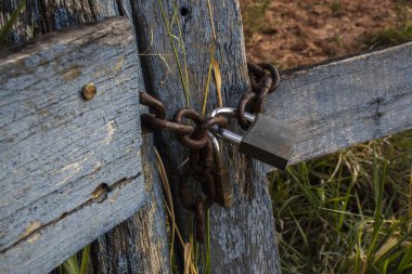 Asma kilit, Brezilya 'nın kırsal kesiminde paslı bir zincirle bir çiftliğin ahşap kapısını kapatıyor.