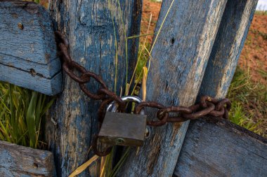 Asma kilit, Brezilya 'nın kırsal kesiminde paslı bir zincirle bir çiftliğin ahşap kapısını kapatıyor.
