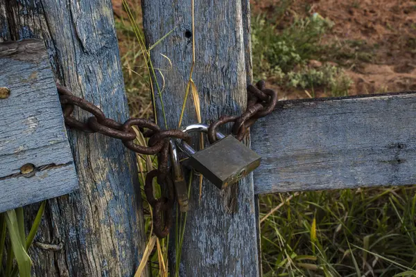 Asma kilit, Brezilya 'nın kırsal kesiminde paslı bir zincirle bir çiftliğin ahşap kapısını kapatıyor.