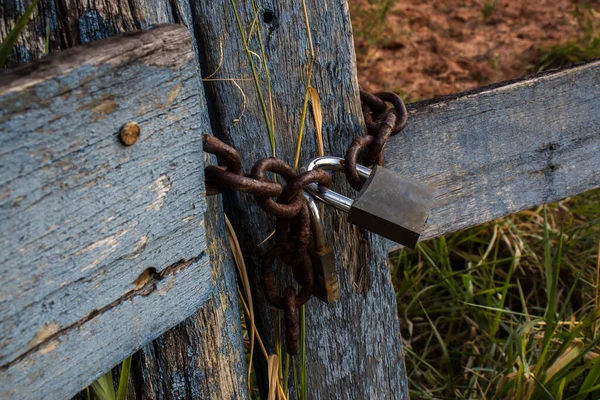 Asma kilit, Brezilya 'nın kırsal kesiminde paslı bir zincirle bir çiftliğin ahşap kapısını kapatıyor.
