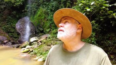 Middle-aged man walks aided by a wooden staff through the Atlantic forest. Apparently tired but happy for the journey in nature
