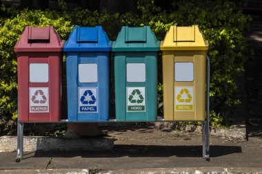Portekizce Plastik, Kağıt, Cam ve Metal kelimeleriyle Brezilya 'daki parkta geri dönüşüm için dört renkli çöp tenekesi