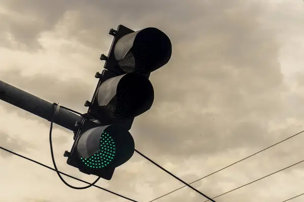 Green traffic signal with sky and clouds background in Brazil.