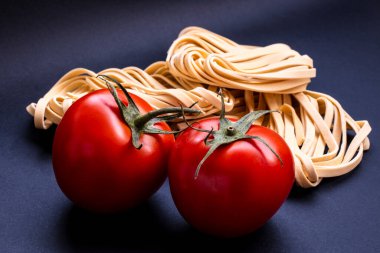 Brezilya 'da mavi arka planda izole edilmiş gerçekçi görünen domatesler ve çiğ makarna