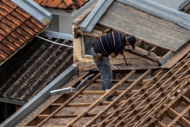 Marilia, Sao Paulo, Brezilya, 29 Ağustos 2023. Marilia şehir merkezindeki ticari bir noktanın çatısını yenilemek için bir evin fayanslarını söken bir işçinin üst görüntüsü