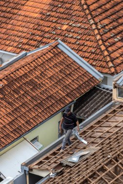 Marilia, Sao Paulo, Brezilya, 29 Ağustos 2023. Şehir merkezindeki ticari bir noktanın çatısını yenilemek için bir evin fayanslarını söken bir işçinin üst görüntüsü 