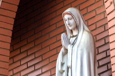 Katolik dininde Tanrı 'nın annesi Fatima' nın heykeli, Fatima 'nın Hanımı, Brezilya' daki tuğla duvarın arka planında Bakire Meryem 'in heykeli.