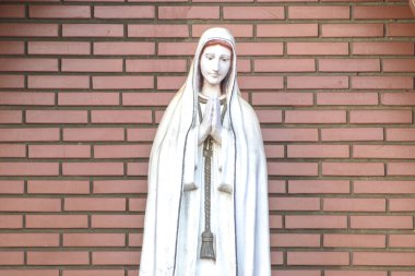 Katolik dininde Tanrı 'nın annesi Fatima' nın heykeli, Fatima 'nın Hanımı, Brezilya' daki tuğla duvarın arka planında Bakire Meryem 'in heykeli.