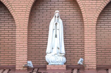 Ftima Anıtı, Katolik dininde Tanrı 'nın annesi, Fatima' nın Hanımı, Brezilya 'da tuğla bir duvarın arka planında Bakire Meryem' in heykeli.